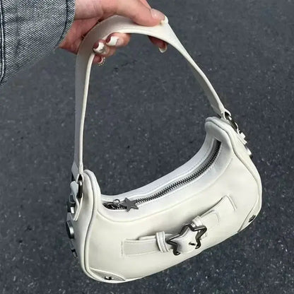 Une main tient le sac fourre-tout à bandoulière vintage coréen mignon blanc Drips-Way, un sac à main en cuir microfibre pour femme avec une fermeture éclair argentée et des accents d'étoiles, sur un fond de trottoir gris.