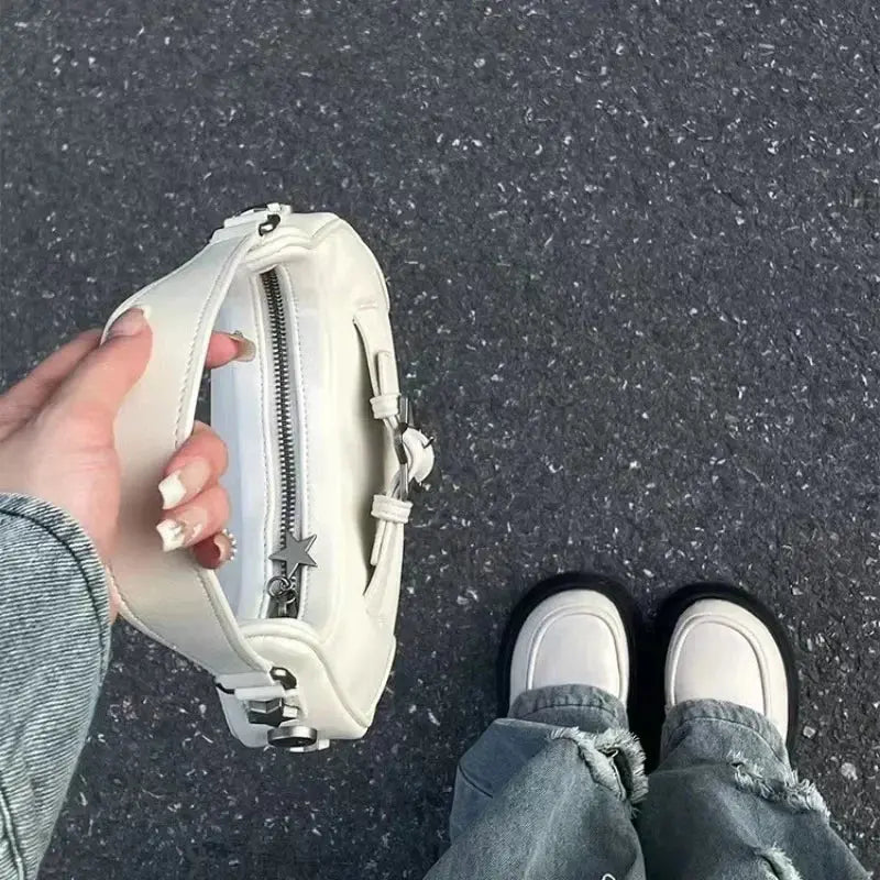 Une personne portant un jean à ourlet effiloché et des chaussures blanches se tient sur l'asphalte, tenant le sac fourre-tout à bandoulière Drips-Way Vintage Korean Casual Cute White Star, un élégant sac à main zippé en cuir synthétique pour femme avec un porte-clés étoile, mettant en valeur un style chic.