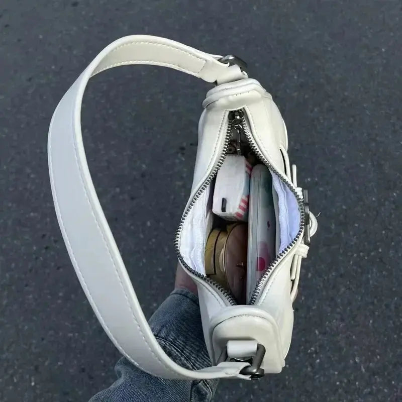 Une personne tient le sac fourre-tout à bandoulière Drips-Way Vintage Korean Casual Cute White Star, dézippé pour révéler des éléments essentiels comme un téléphone et du maquillage, sur un trottoir gris - un instantané chic de cet élégant sac à main en cuir microfibre.