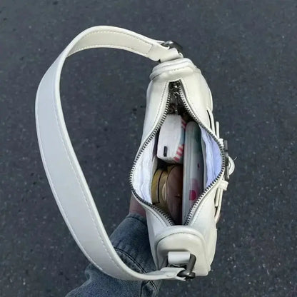 Une personne tient le sac fourre-tout à bandoulière Drips-Way Vintage Korean Casual Cute White Star, dézippé pour révéler des éléments essentiels comme un téléphone et du maquillage, sur un trottoir gris - un instantané chic de cet élégant sac à main en cuir microfibre.